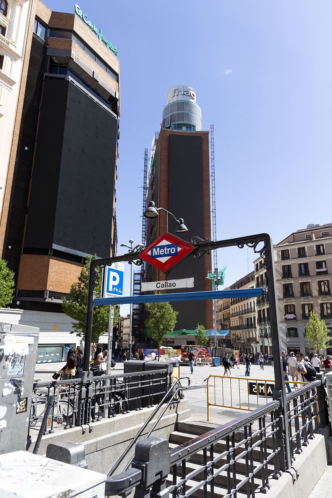 Entrada de la estación de metro de Callao en Madrid, con edificios y gente cruzando la plaza